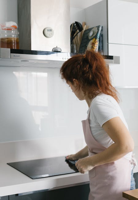 A close-up view of an open dishwasher with clean, stainless steel interior components, including the racks and cutlery basket, positioned in a modern kitchen space. The dishwasher racks are empty and 